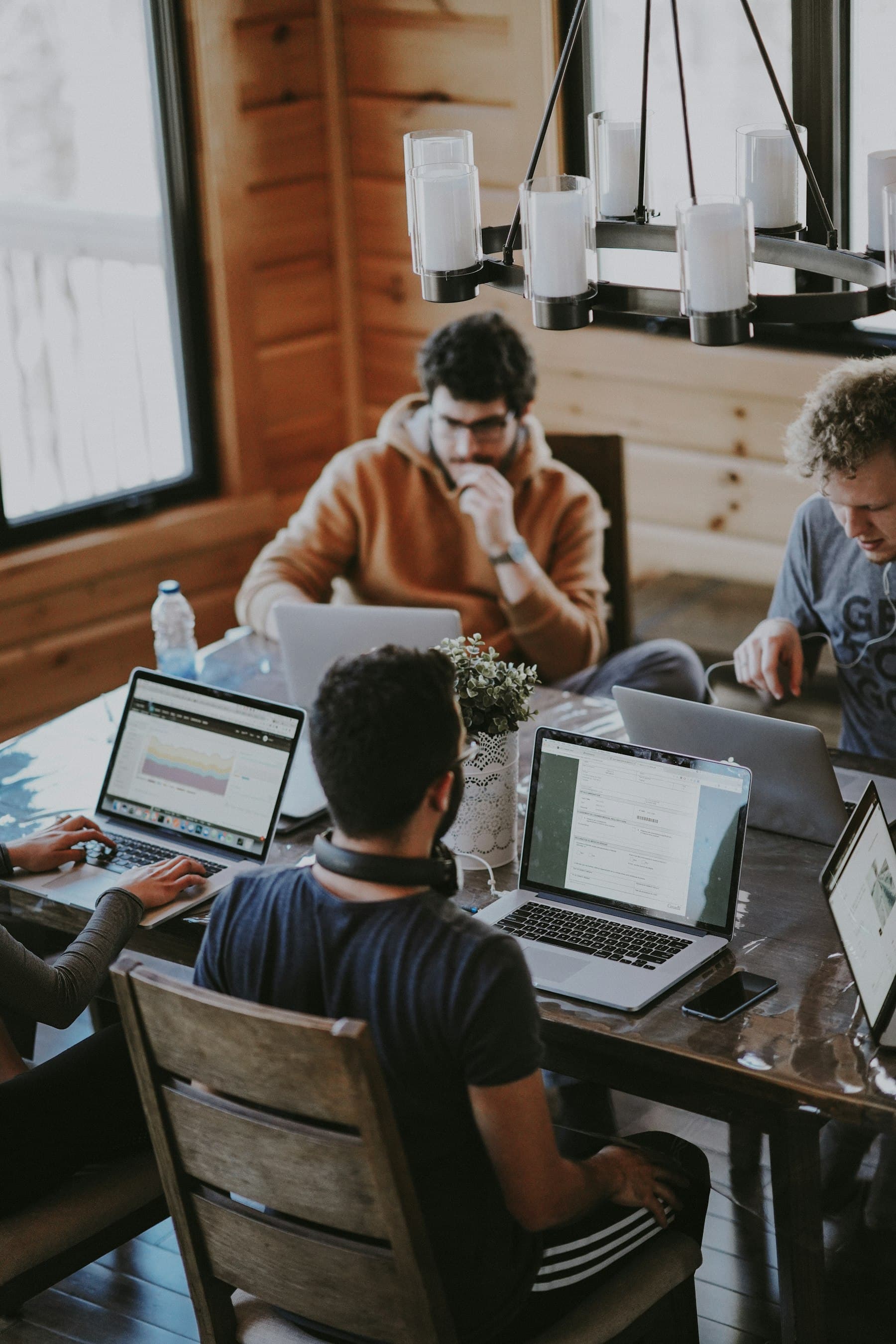 People gathered around laptops at a wooden table
