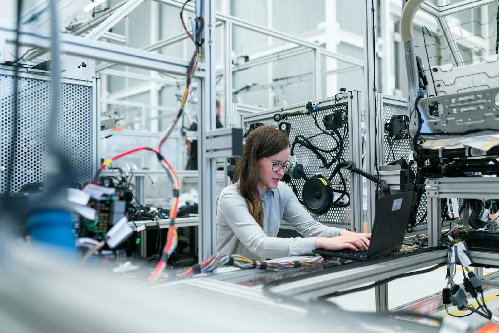 A person working on a laptop beside industrial equipment